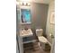 Bathroom with sink, toilet, and gray-green walls, illuminated by a three-bulb vanity light at 2691 Old South Dr, Jonesboro, GA 30236