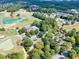 Aerial view showcases a golf course, tennis courts, a community pool, and a clubhouse surrounded by trees at 3150 Seven Oaks Dr, Cumming, GA 30041