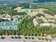 Aerial view highlighting the golf course, tennis courts, and community pool surrounded by trees at 3150 Seven Oaks Dr, Cumming, GA 30041
