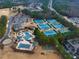 Aerial view showcasing tennis courts, swimming pool, clubhouse, and parking areas, surrounded by trees at 3150 Seven Oaks Dr, Cumming, GA 30041