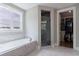 Bright bathroom showcasing a soaking tub, glass-enclosed shower, and walk-in closet at 130 Lapis Lake Pt, Fayetteville, GA 30215