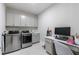 Well-organized laundry room with modern washer and dryer set, a utility sink, and a built-in desk at 130 Lapis Lake Pt, Fayetteville, GA 30215