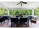 Outdoor patio with ceiling fan, wood flooring, outdoor table, seating, and views of the wooded backyard at 130 Lapis Lake Pt, Fayetteville, GA 30215