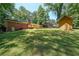 Expansive backyard view showcasing the brick home, deck, and a small shed against a backdrop of green lawn and trees at 213 Linda Dr, Tucker, GA 30084