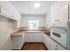 Compact kitchen with white cabinetry, updated appliances, and hardwood floors at 213 Linda Dr, Tucker, GA 30084