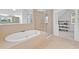 A luxurious bathroom featuring a soaking tub, glass shower, and open shelving for storage at 602 Davenport Pl, Canton, GA 30115