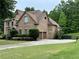 Side exterior view of a two-story brick home showcasing the attached garage and well-maintained lawn at 602 Davenport Pl, Canton, GA 30115