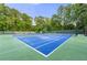 Brightly painted tennis court featuring meticulously maintained landscaping and surrounding mature trees at 4343 Sprucebough Dr, Marietta, GA 30062