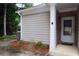Side exterior of a home with gray siding, white trim, and a covered entryway, surrounded by green trees and foliage at 179 Camry Ln, Grayson, GA 30017