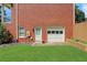 Brick exterior with white garage door surrounded by green lawn and a small garden area, adding charm to the backyard at 2535 Winthrope Way, Lawrenceville, GA 30044