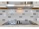 Close up of a kitchen backsplash with grey and white tiles and stainless steel stovetop at 2535 Winthrope Way, Lawrenceville, GA 30044