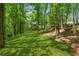 Sprawling backyard featuring a lush lawn, tall trees and a home with a charming deck at 950 Ivy St, Cumming, GA 30041
