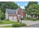 Classic brick home with a two-car garage, mature trees, well-kept lawn, and tidy landscaping at 2018 Township Dr, Woodstock, GA 30189