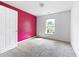 An empty bedroom with a bold pink accent wall and natural light from the window at 6770 Gordon Manor Sw Ct, Mableton, GA 30126