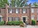 Charming brick townhouse featuring symmetrical design, black shutters, and manicured landscaping at 70 Old Ivy Ne Rd # 57, Atlanta, GA 30342