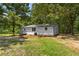 Single-story home with white siding and dark roof surrounded by lush, mature trees at 2871 Tucker Mill Sw Rd, Conyers, GA 30094