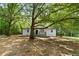 Single-story home featuring a cozy front porch shaded by mature trees at 2871 Tucker Mill Sw Rd, Conyers, GA 30094
