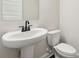 Well-lit powder room featuring white pedestal sink and toilet at 5120 Kongoni Ct, Cumming, GA 30041