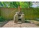 A rustic stone oven with a chimney stands against a wooden fence in a backyard setting at 1844 Stanton St, Decatur, GA 30032