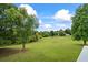 Large, expansive green backyard with a few trees scattered around on a sunny day with a few clouds at 4914 Watson Mill Ct, Loganville, GA 30052