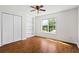 Bright bedroom with wood-look flooring, a window overlooking the yard, and a built-in shelving unit at 4914 Watson Mill Ct, Loganville, GA 30052