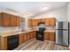 Efficient kitchen with stainless steel refrigerator, black appliances, wooden cabinets, and wood-look floors at 1034 Sandy Ridge Rd, Mcdonough, GA 30252