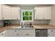 This kitchen features white cabinets, granite countertops and a view of the trees at 6375 Eidson Dr, Cumming, GA 30041