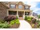 Inviting front porch with a stone accent wall and decorative landscaping at 6585 Canyon Cv, Cumming, GA 30028