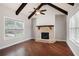 Living room featuring a brick fireplace, wood floors, and large windows for natural light at 6585 Canyon Cv, Cumming, GA 30028