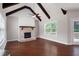Bright living room featuring a brick fireplace, wood floors, and large windows for outdoor views at 6585 Canyon Cv, Cumming, GA 30028