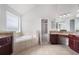 Bright primary bath with tile floors, a soaking tub, dual sink vanity, and make up counter at 6585 Canyon Cv, Cumming, GA 30028