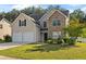 Traditional home featuring a well-kept lawn, double garage, and stone facade at 211 Millstone Dr, Hampton, GA 30228