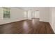 Open living room featuring dark wood-look flooring and natural light from large windows at 211 Millstone Dr, Hampton, GA 30228