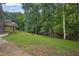 Green backyard with trees and grassy area surrounding the home with patio and wooden deck at 4070 Feather Dr, Douglasville, GA 30135