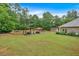 Expansive backyard with lush lawn, mature trees, sparkling pool, outdoor seating, and shed at 7030 Mandevilla Ln, Douglasville, GA 30135