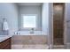 Elegant bathroom featuring a soaking tub with stone surround and a glass shower enclosure at 799 Wagon Trl, Woodstock, GA 30188