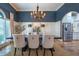 Elegant dining room featuring stylish chairs, modern chandelier, and seamless flow to the kitchen at 799 Wagon Trl, Woodstock, GA 30188