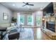 Bright living room with hardwood floors, stone fireplace, and large windows to a green outdoor space at 799 Wagon Trl, Woodstock, GA 30188