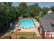 Community pool with a fence, ample lounge chairs, tables with umbrellas, and surrounded by mature trees at 6004 Turfway Park Ct, Sugar Hill, GA 30518
