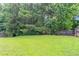 Spacious grassy backyard surrounded by mature trees and a wooden privacy fence at 7190 Cavender Sw Dr, Atlanta, GA 30331