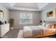 Staged bedroom with neutral decor, large window, tray ceiling, and contemporary furnishings at 7190 Cavender Sw Dr, Atlanta, GA 30331