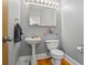 Modern powder room featuring a pedestal sink, toilet, and a large mirror with stylish lighting at 2700 Still Farms Ct, Lawrenceville, GA 30043
