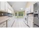 Galley kitchen with white cabinets, stainless steel appliances, and a breakfast nook with backyard access at 467 Ravinia Way, Lawrenceville, GA 30044