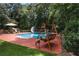 Backyard view of the in-ground pool, swing, patio and seating, with mature trees at 5778 Little Oak Trl, Stone Mountain, GA 30087