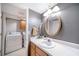 Bright bathroom featuring a round mirror, single sink vanity, and a washer and dryer inside the closet at 5778 Little Oak Trl, Stone Mountain, GA 30087