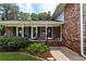 Covered front porch with brick accents, rocking chairs, and a charming entrance to the home at 5778 Little Oak Trl, Stone Mountain, GA 30087