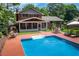 Backyard view of a brick home with a screened porch, in-ground pool, and lounge seating area at 5778 Little Oak Trl, Stone Mountain, GA 30087