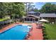 A backyard view of the inground pool with a slide, patio seating, swing and brick home at 5778 Little Oak Trl, Stone Mountain, GA 30087