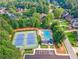 Aerial view showcasing tennis courts, a pool, and surrounding greenery of the neighborhood at 4750 Freeport Bay Ne, Roswell, GA 30075