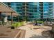 A stone patio area outside of a luxury condo building with tables, chairs, and manicured landscaping at 943 Peachtree Ne St # 1518, Atlanta, GA 30309